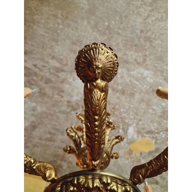 Eight-arm cast chandelier made of polished brass. Rich plant and figural decoration. The chandelier is for classic candle...
