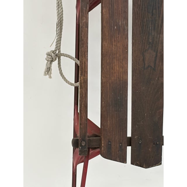 Classic vintage Gladding “American Flyer” wooden sled with red-painted metal runners, bentwood-style handle assembly, and...