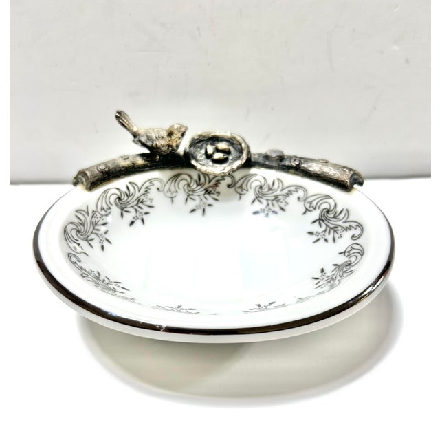 A beautifully detailed, footed porcelain soap dish. It has a bird on a branch with a little nest with tiny eggs inside....