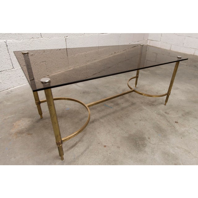 1960s coffee table in gilt brass and smoked glass. Tabletop dimensions: 90 x 45 cm height: 39.5 cm It is in good...