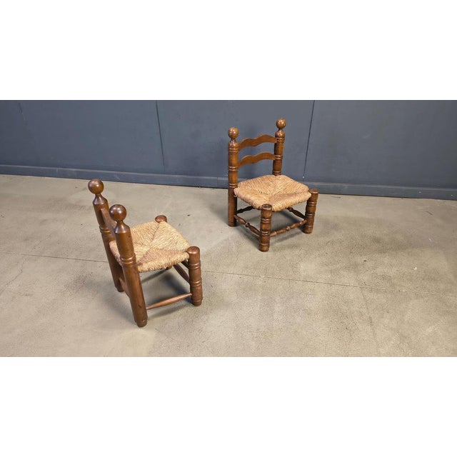 Sturdy brutalist side chairs or children chairs attributed to Charles Dudouyt. Made from stained oak and wicker seats....