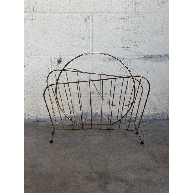 This striking wire magazine holder features a gleaming brass finish and a convenient arched handle. Its open geometric...