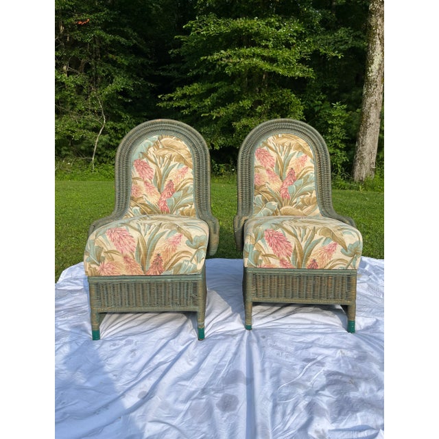 A matching pair of unique wicker chairs with curved backs and upholstered seats and seat backs. Chairs feature original...