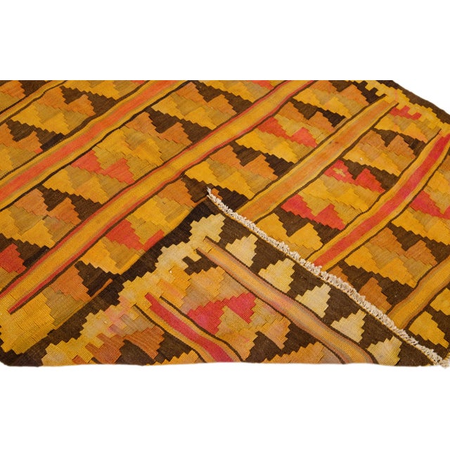 Beautiful vintage Turkish Kilim hand-knotted wool runner with an orange field. This rug has a yellow frame and multicolor...