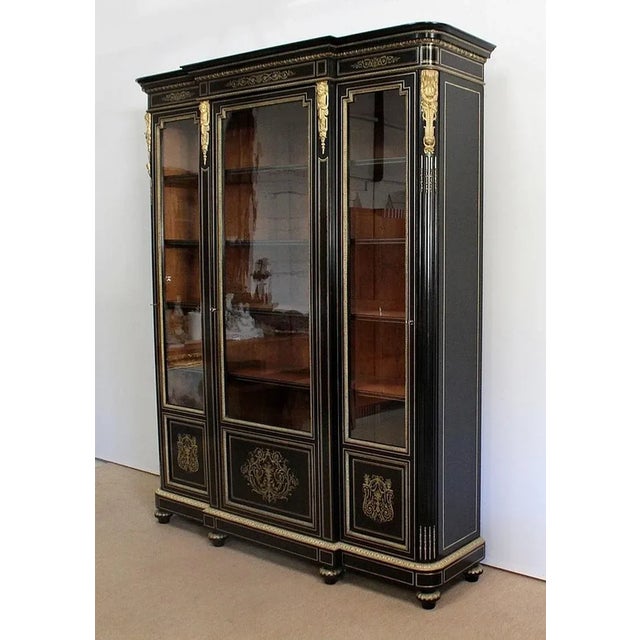 Large and elegant Napoleon III library in blackly ornamented black pear, opening by three doors with five shelves. This...