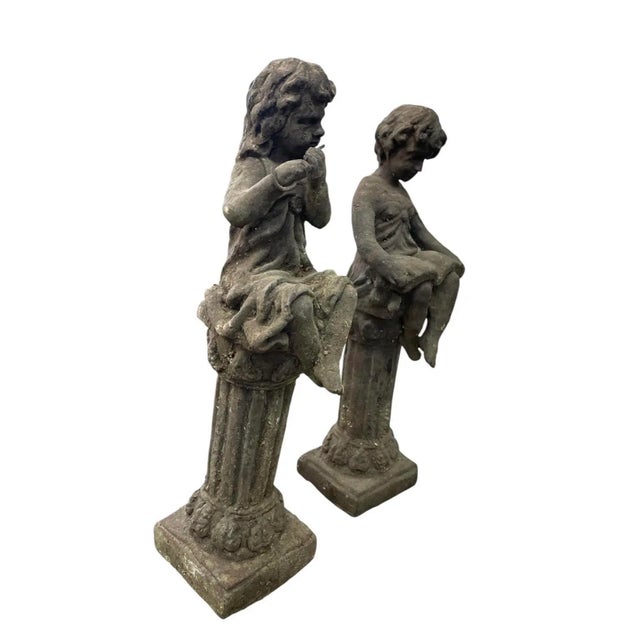 An enchanting and finely detailed pair of vintage cast iron garden or solarium statues depicting classical seated...