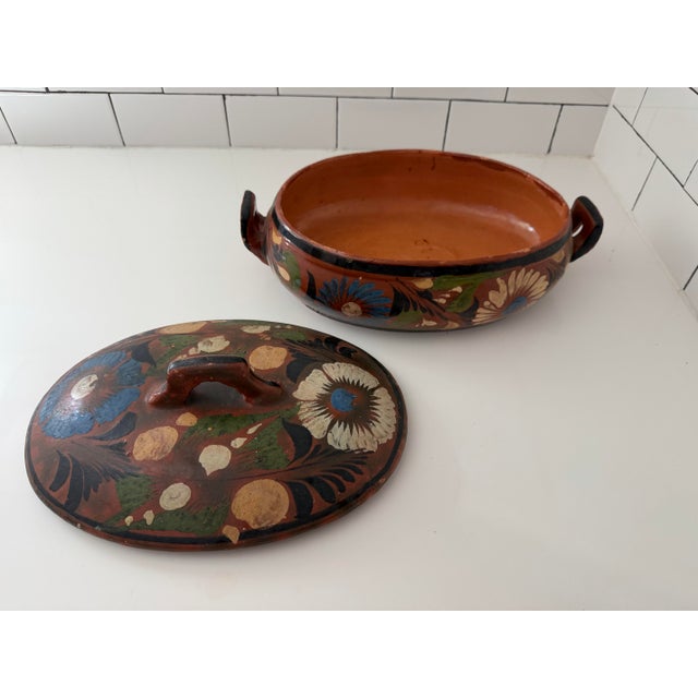 This is a vintage Mexican Tlaquepaque redware lidded casserole dish featuring a hand-painted floral folk art motif. These...