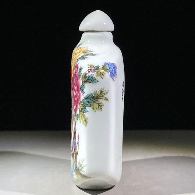 This is a charming vintage porcelain snuff bottle, decorated in the famille rose palette with vibrant polychrome enamels....
