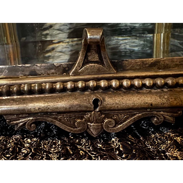 Up for sale is an absolute masterpiece of old-world European craftsmanship: a grand, heavy-framed antique tabletop vitrine...