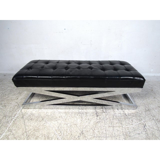 Stylish modern upholstered bench. Sturdy X-frame chrome base. The padded seat is covered in a black tufted faux-leather...