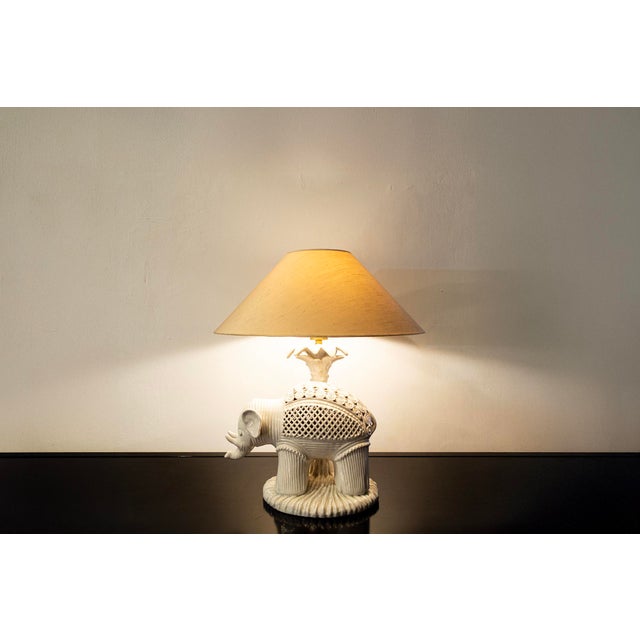 Elephant-shaped lamp in white ceramic casting with fretwork, brass details, paper lampshade. Italian production 70s...