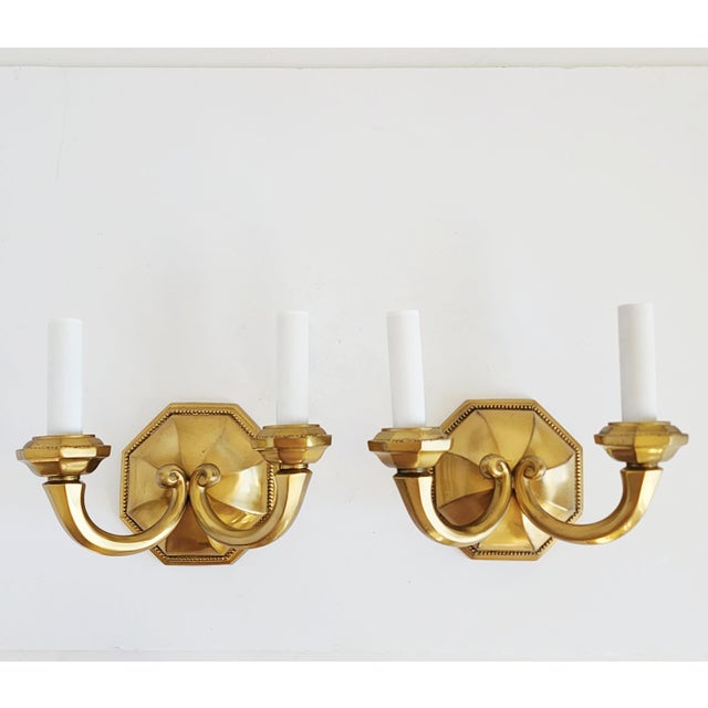 Early 20th century English Georgian style cast brass wall sconces with twin-arm. Featuring a satin brass finish, octagonal...