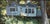 Cottage Life by Sheri Farabaugh | Oil on Hardboard Painting of a blue cottage surrounded by greenery For Sale