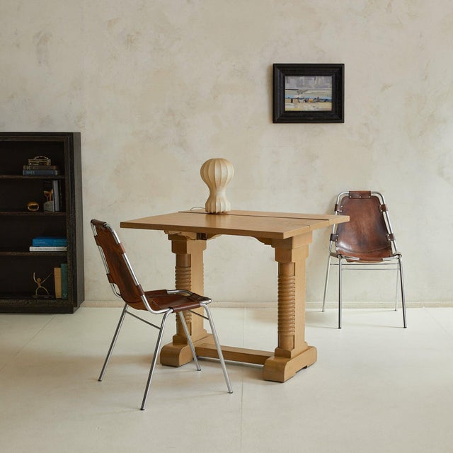 A 1940s French oak drop-leaf side table in the manner of Charles Dudouyt. The rectangular top extends with hinged leaves,...