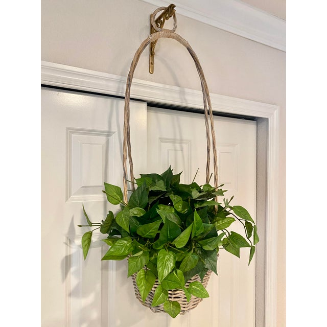 Vintage Unique Woven Rattan Hanging Basket. It features a woven round base and a uniquely high, arched handle with a small...