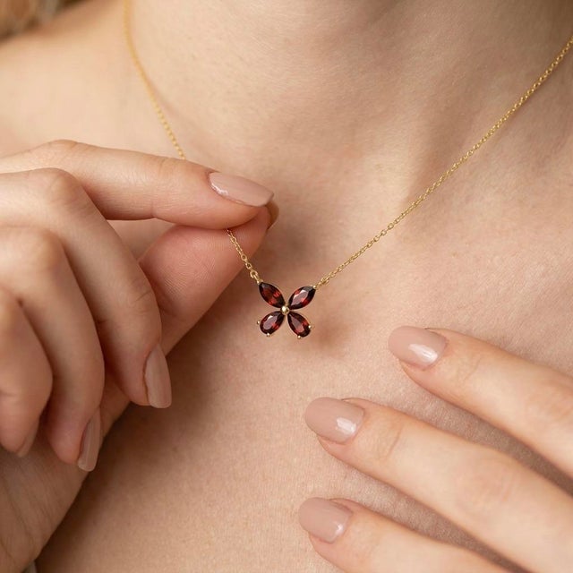 This delicate and charming necklace features a beautiful four-leaf clover pendant, crafted from four marquise-cut, deep...