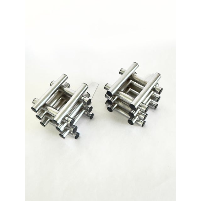 A pair of artist-made architectural bookends consisting of stacked & welded stainless steel rods with black plastic end...