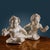 Antique angles in Carrara marble, depicted in a mirror image of each other: limply reclining, the bust advanced and with a...