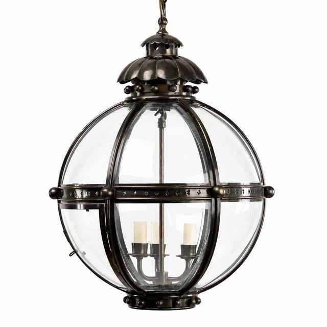 A substantial bronze and brass hall lantern with curved glass panels and elegant segmented oval form. The fixture features...