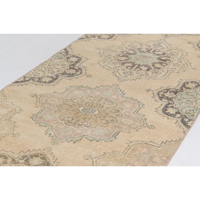 This is a vintage Turkish Oushak rug from the Mid 20th Century. The piece was hand-knotted.