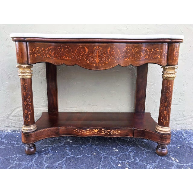 Early 19th century console in wood veneer with a white marble top. It features beautiful marquetry of rinceaux and floral...