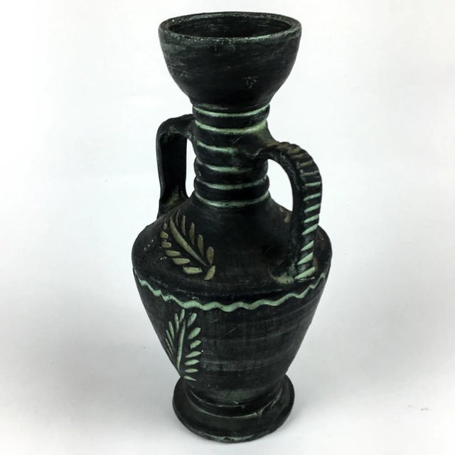 Unusual carved rustic design with pale green under glaze and black rubbed finish. This cool vase will look great in your...