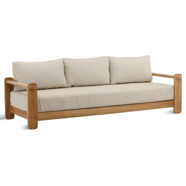 Outdoor solid natural teak wood frame sofa with soft taupe cushions. Each sofa may vary in exact coloring, wood grain, and...