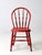 An antique bow back Windsor chair in richly aged red paint, presenting a classic early American silhouette with quiet...
