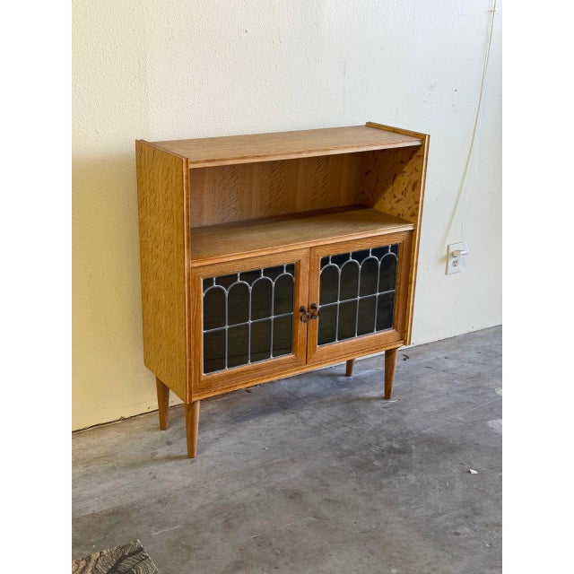 Beautiful vintage Danish oak cabinet featuring decorative leaded glass doors and a warm honey-toned oak grain throughout....