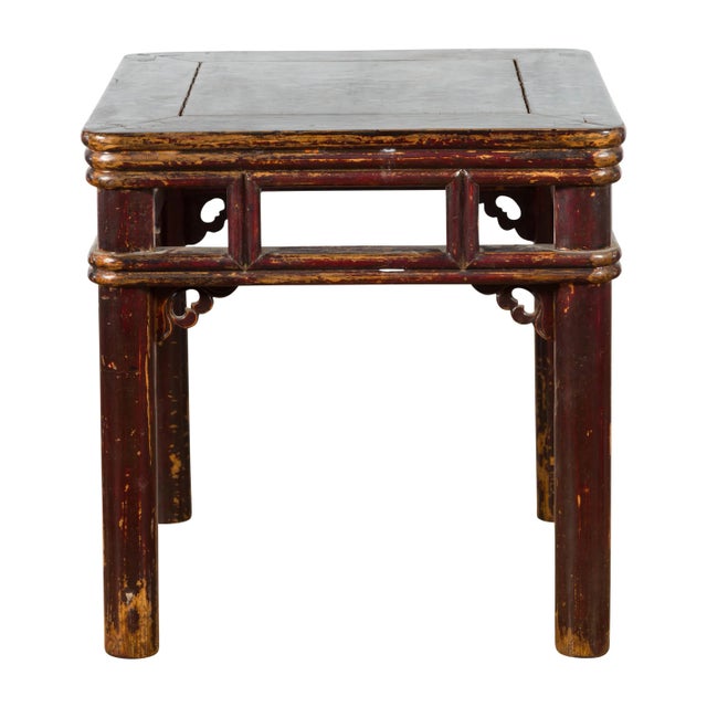A Chinese Qing Dynasty period elm wood side table from the 19th century, with open apron, carved spandrels, pillar strut...