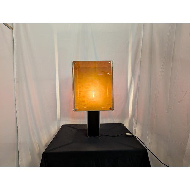 This table lamp is a refined example of 1970s design, featuring a geometric aesthetic that combines a glossy black column...