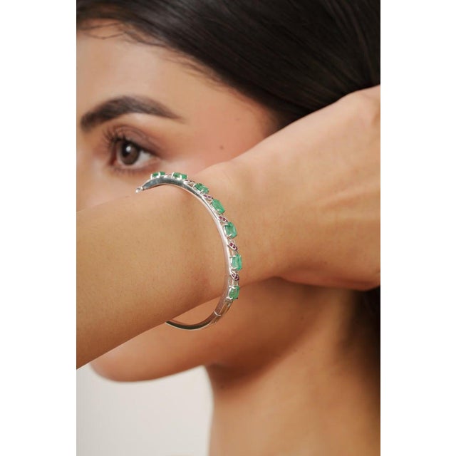 This elegant vintage bangle is crafted in 925 sterling silver and beautifully set with natural emerald and ruby gemstones....
