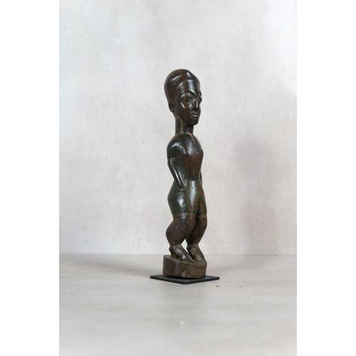Hand-carved from indigenous wood, this figure comes from the Baule people of the Ivory Coast. Deeply rooted in Baule...