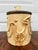 Ceramic cookie jar made by Metlox poppytrail. It has a creamy glaze and raised bird embellishments, and on top rests a...