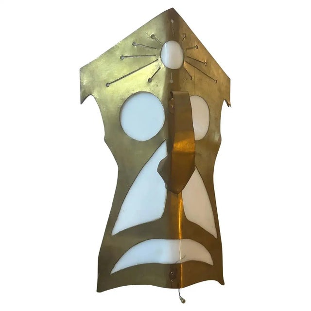 An hand-crafted brass and white plexiglass wall light depicting a tribal mask, it has been manufactured in Italy in the...