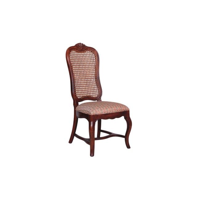 A set of six French Country style dining chairs. Tall, caned seat backs are decorated with carved shell details on the...