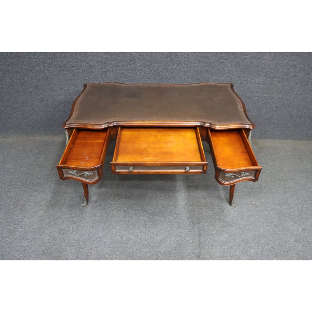 French Provincial–style writing desk crafted in warm walnut with a shaped top and cabriole legs. The desktop is finished...