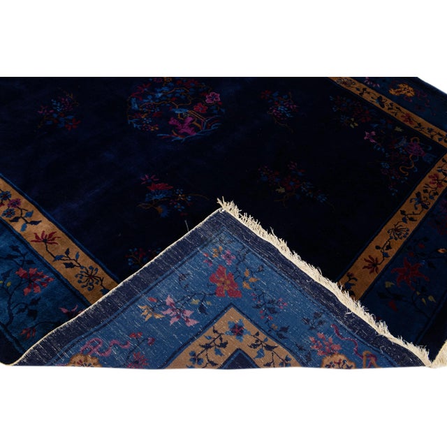 Beautiful antique Peking Chinese hand-knotted wool rug with a navy blue field. This Chinese rug has a tan frame with...