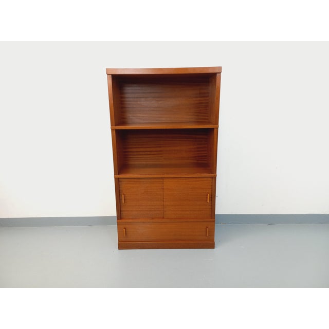 Vintage 1960s bookcase in dark oak, with a solid plinth, two open shelves, two sliding doors, and one large drawer at the...