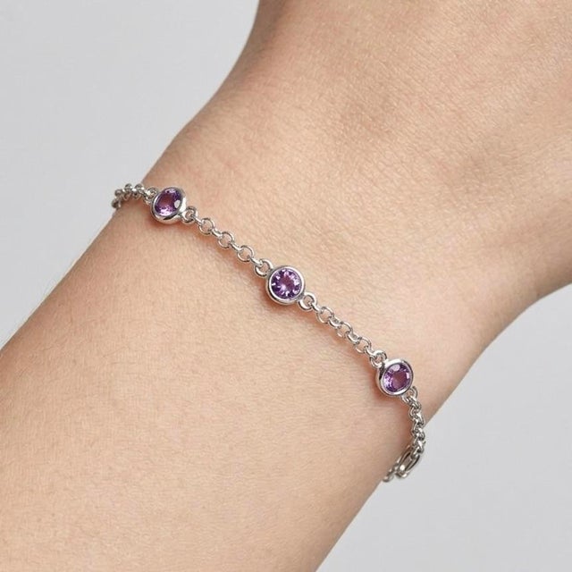 Graceful and refined, this elegant bracelet features soft violet gemstones delicately set along a fine silver...