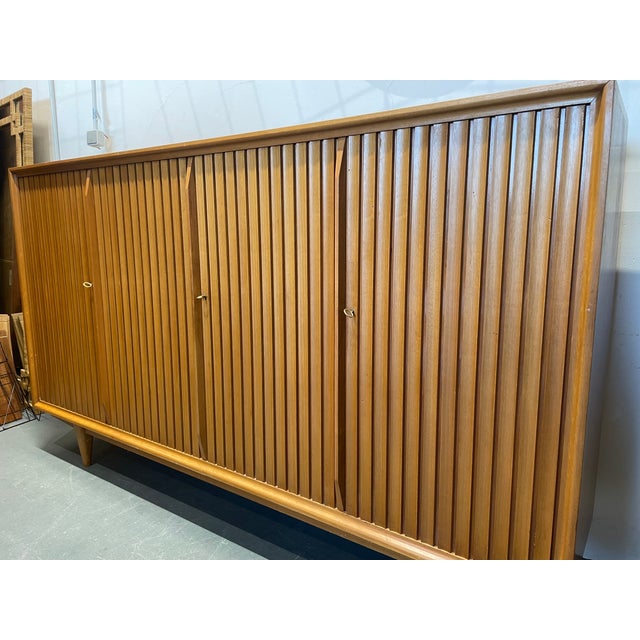 This large, symmetrical highboard, designed by Leo Bub and made in Germany, offers ample storage space thanks to its size....