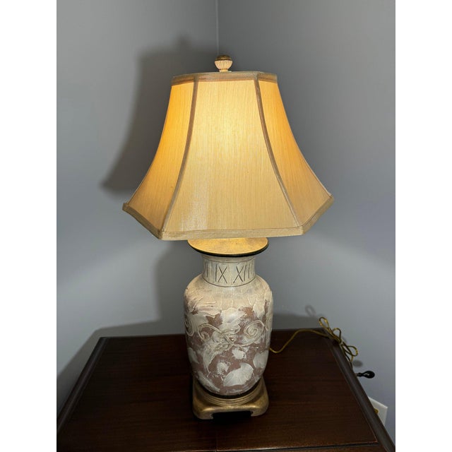 Elegant and sculptural pottery table lamp featuring a classic urn-shaped base adorned with hand-finished gilded detailing...