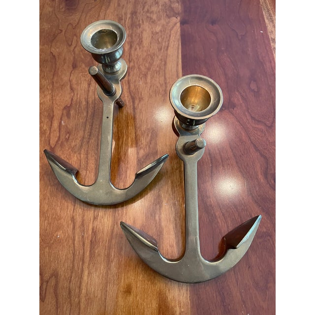 Pair of vintage mid-century modern brass candlesticks in a decorative nautical motif. The "anchors" sit on a table top or...