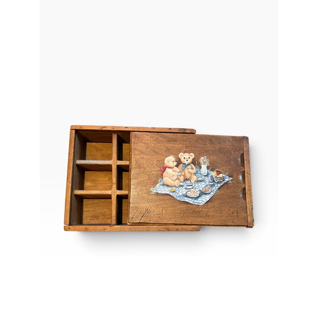 Charming vintage wooden storage box featuring a sweet illustrated teddy bear picnic scene on the sliding lid. The warm-...