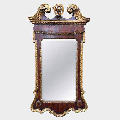 A Georgian pier mirror in walnut and Giltwood. The broken pediment top with scrolls and rosettes, gilt outer border with...
