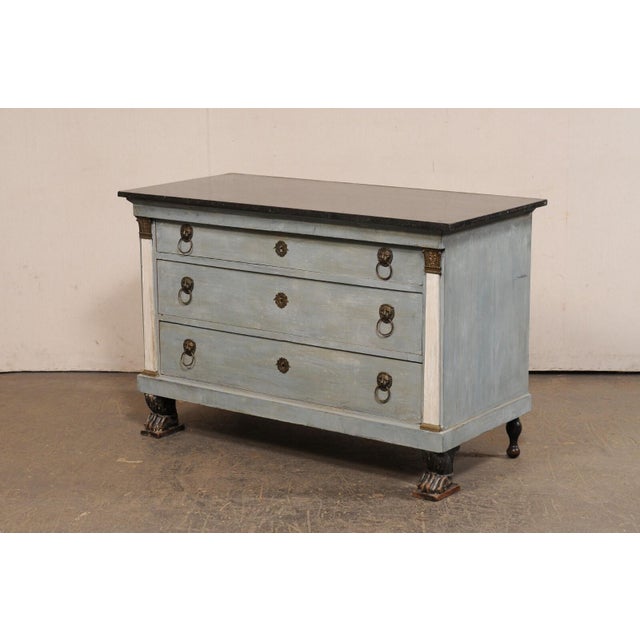 A French Neoclassical marble-top chest of three drawers from the 19th century. This antique commode from France features a...