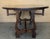 A rustic Spanish walnut drop-leaf table from the 20th century with round top, lyre legs and low stretchers . Embrace the...
