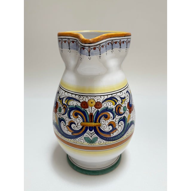 Hand-painted pottery pitcher from Italy featuring the iconic Ricco pattern with scrollwork and floral accents, inspired by...