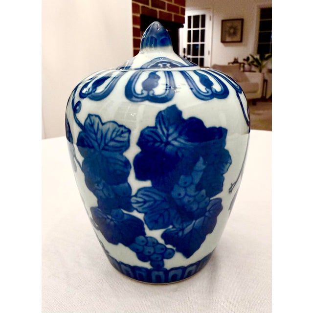 A study in timeless elegance, this substantial blue and white porcelain ginger jar is wrapped in a lush, hand-painted...