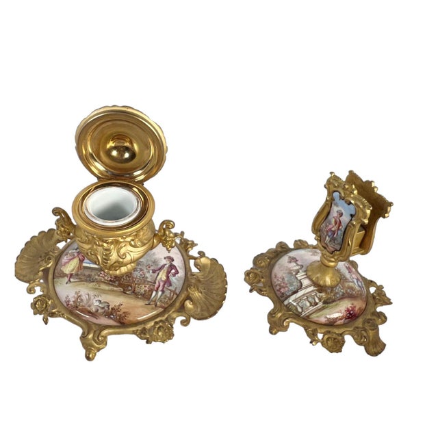 This exquisite French enamel and bronze inkwell and match holder set, adorned with hand-painted figures, is a stunning...